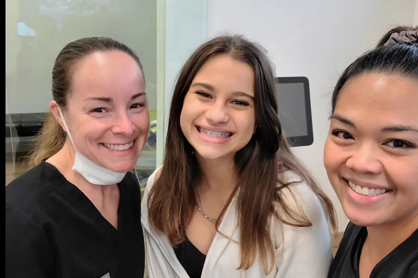 Certified dental assistants take a photo with a patient.