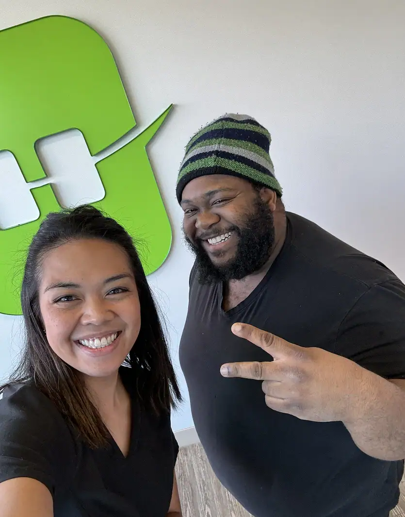 Two smiling people taking a selfie by the Straight Smiles logo